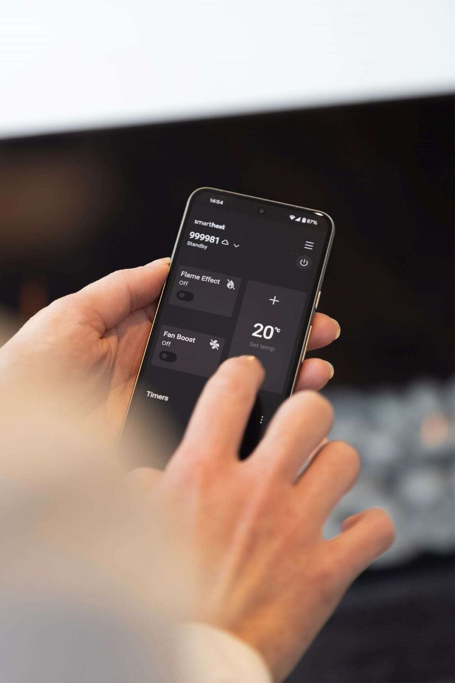 A hand holding a phone showing the SmartHeat app with the temperature set to 20 degrees